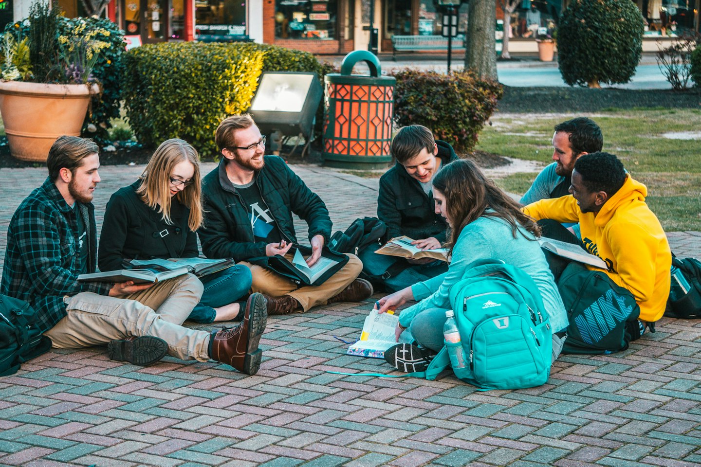 Young adults studying together outdoors on a brick patio.