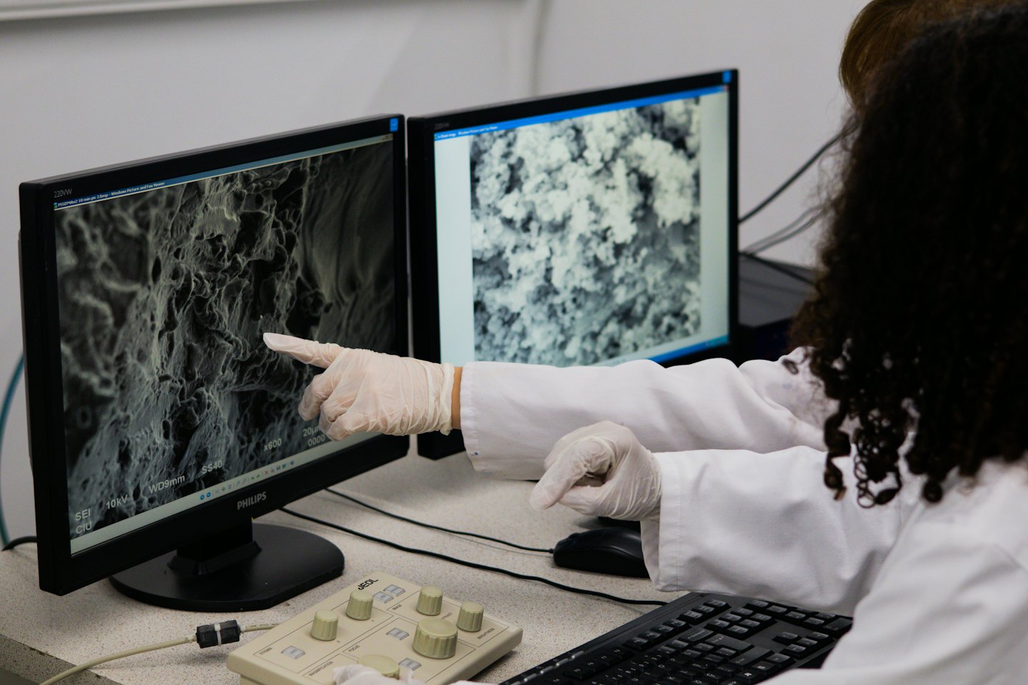 Researcher analyzes electron microscopy image on computer monitors in lab.